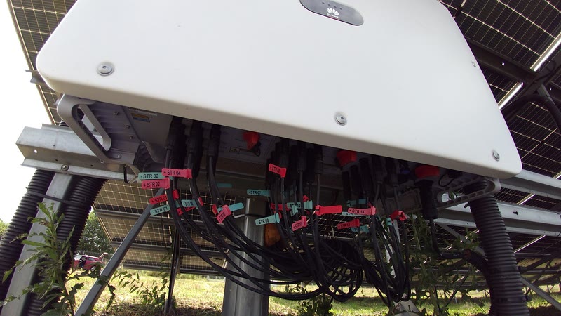 String inverter with labelled DC string connections on a utility-scale solar array
